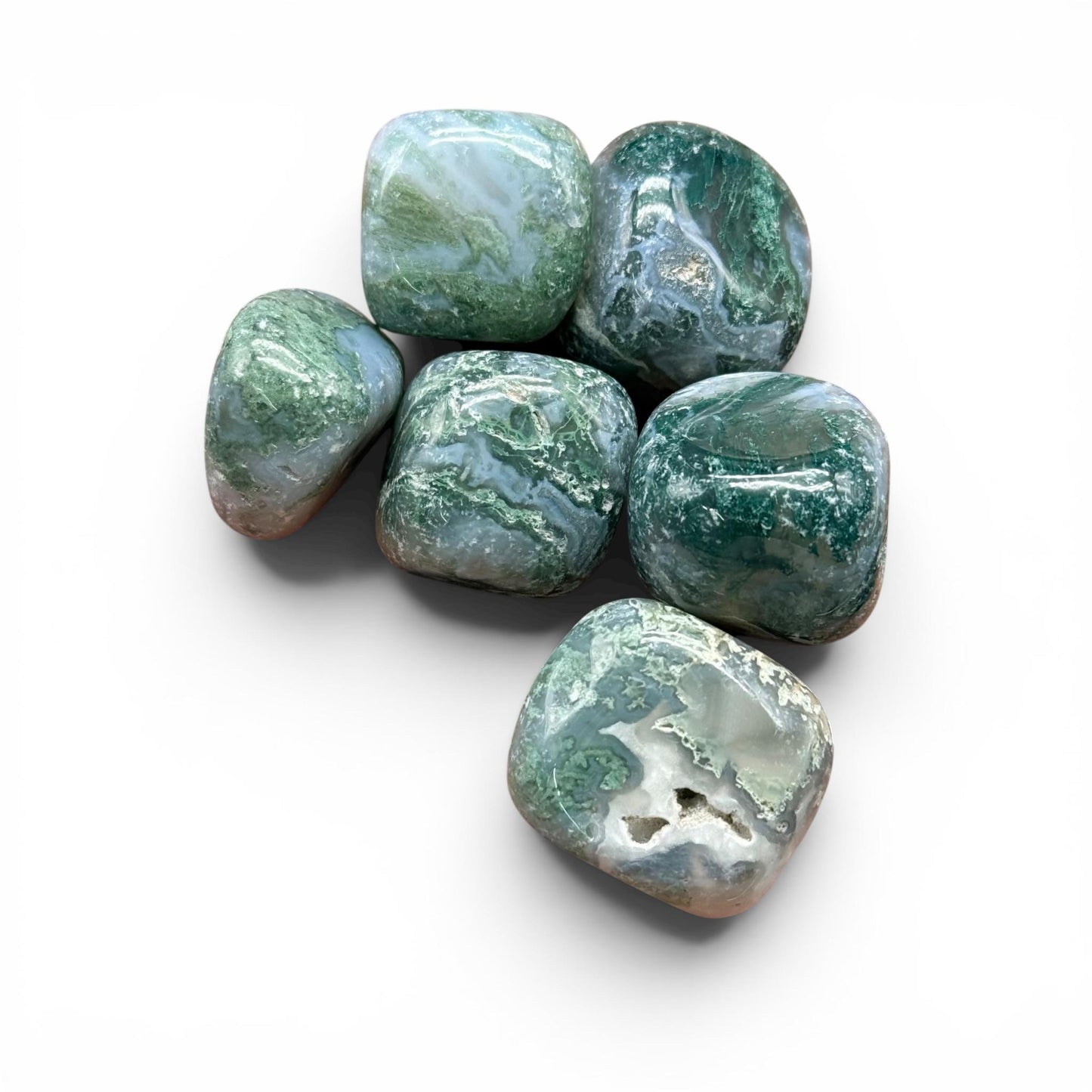 Natural moss agate tumble stones grouped on white background, green and blue veining