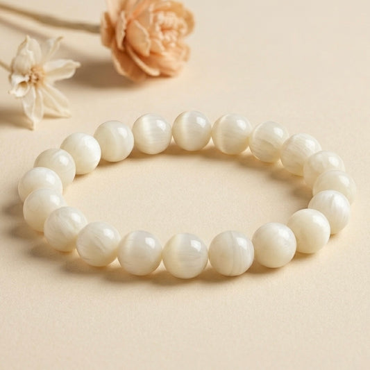 Mother of Pearl beaded bracelet with silver center bead on light beige fabric