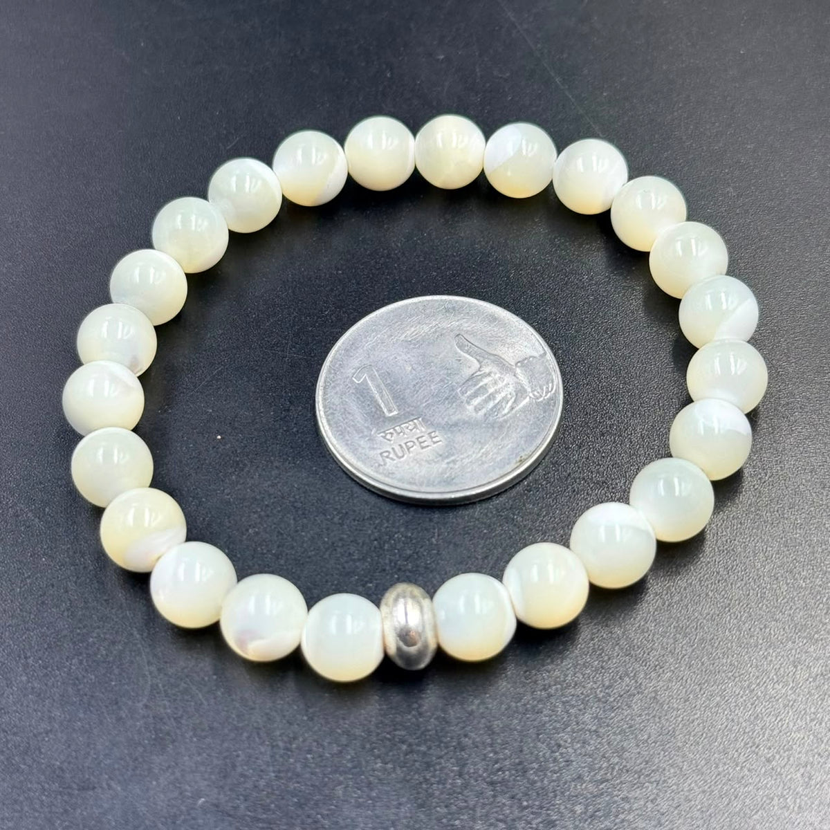 Mother of Pearl bracelet beads with silver spacer, shown on dark blue textured background