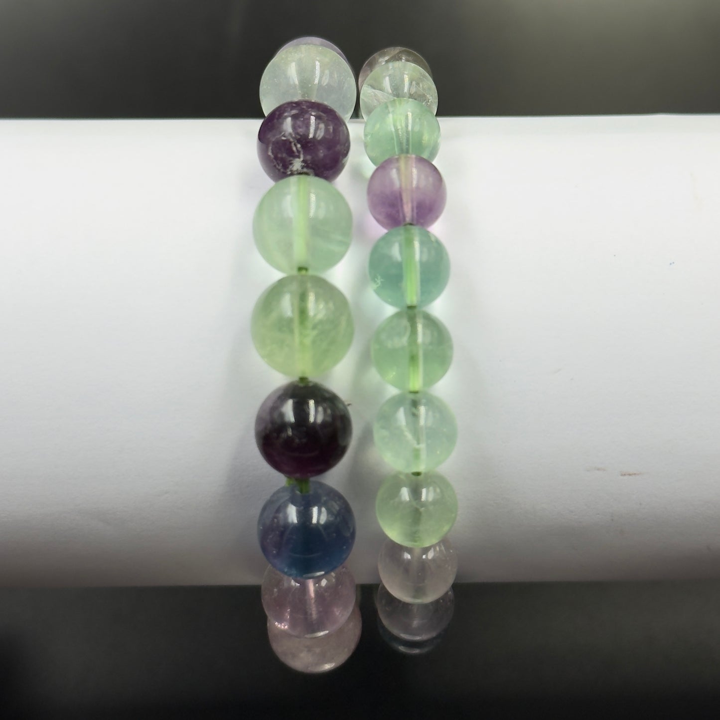Multi fluorite bracelet beads close-up with soft reflection on white background