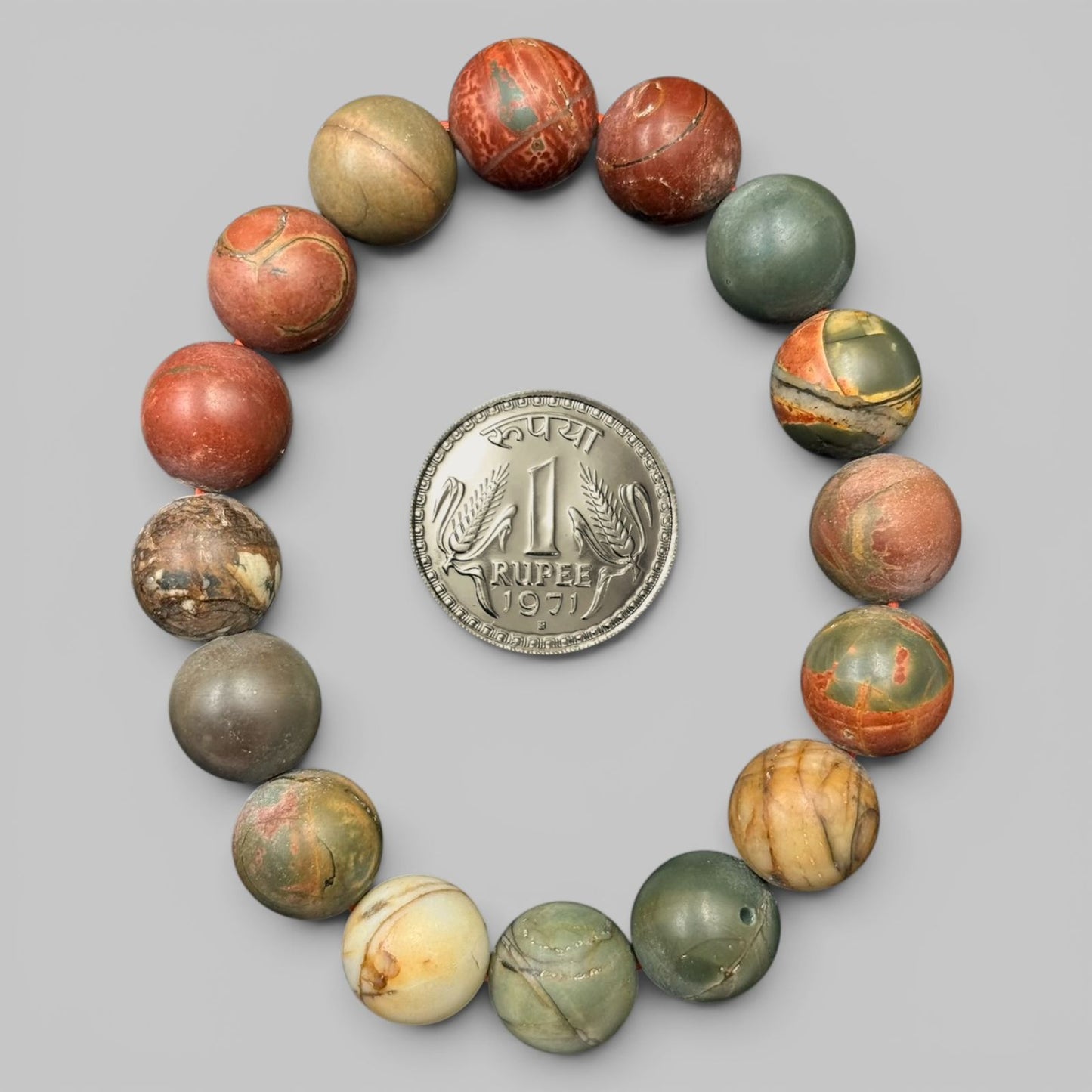 Multi Picasso jasper bracelet beads arranged in circle with coin for scale