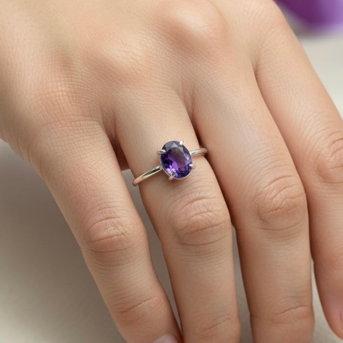 Close-up of natural amethyst adjustable ring on hand with purple oval gemstone setting