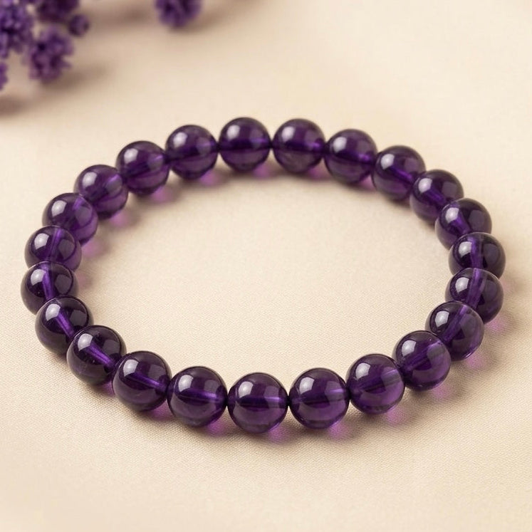 Round natural amethyst beads bracelet on beige fabric background with soft purple flowers
