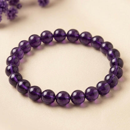 Round natural amethyst beads bracelet on beige fabric background with soft purple flowers