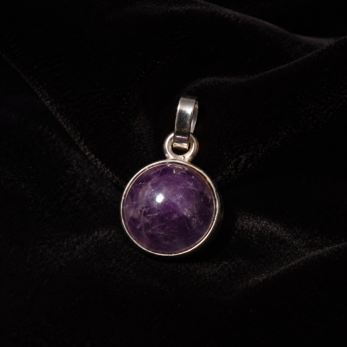 Natural amethyst cabochon pendant in German silver on black velvet background