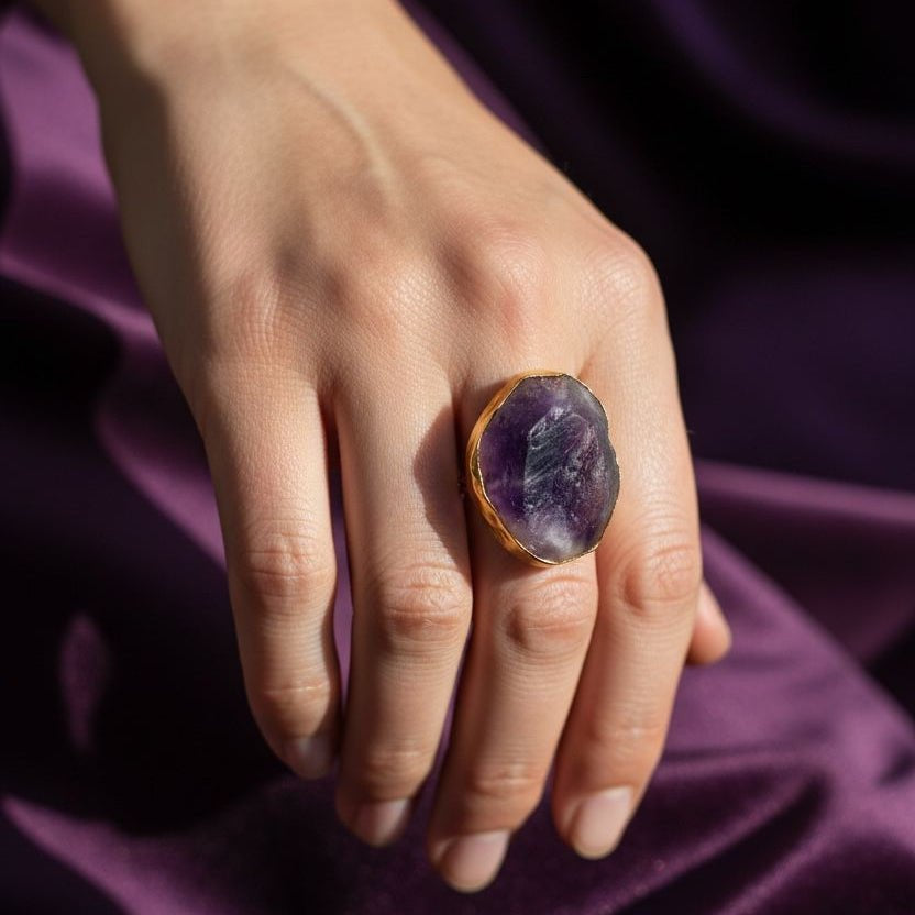 Natural amethyst rough ring held on hand with gold metal band