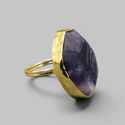 Natural amethyst rough ring with gold band side view on light gray background