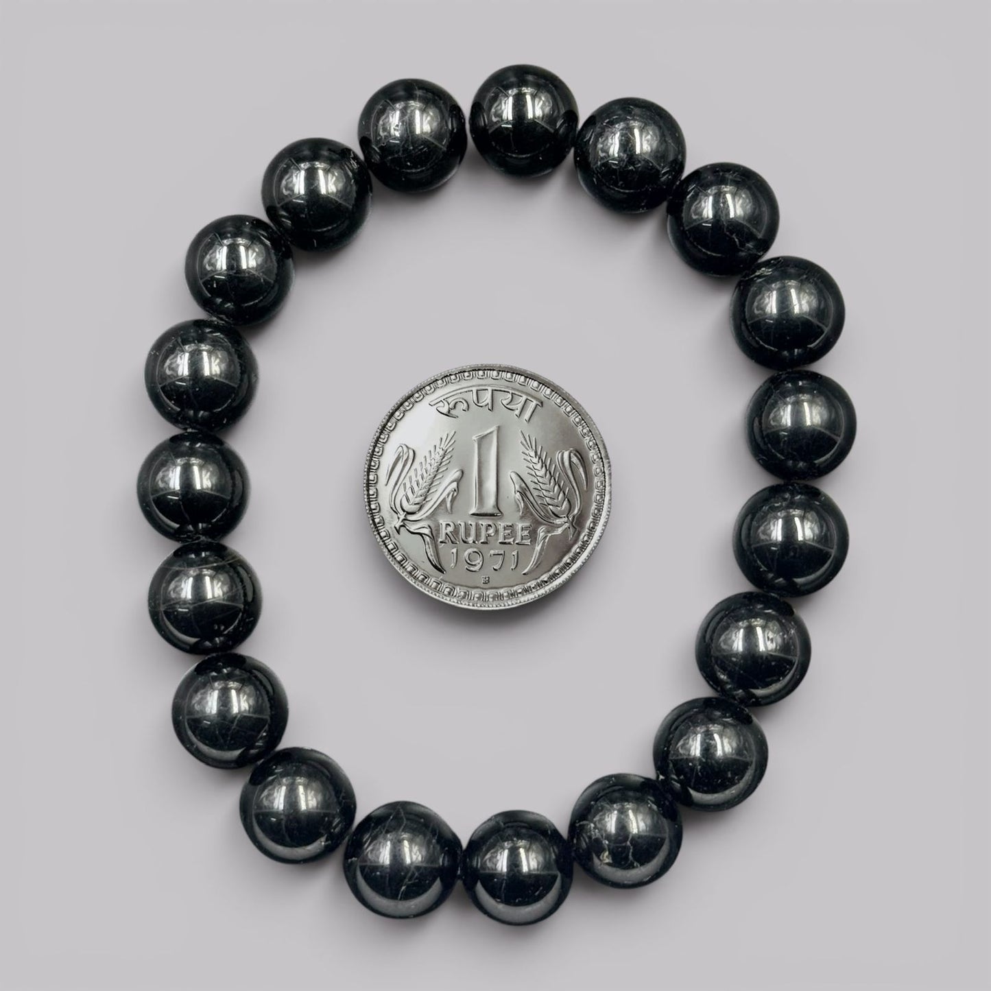 Natural black tourmaline bracelet beads with coin shown for size reference