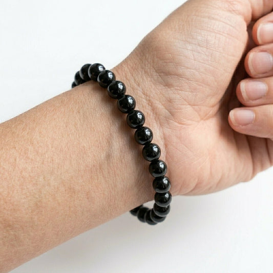 Natural black tourmaline bead bracelet worn on wrist with glossy round beads