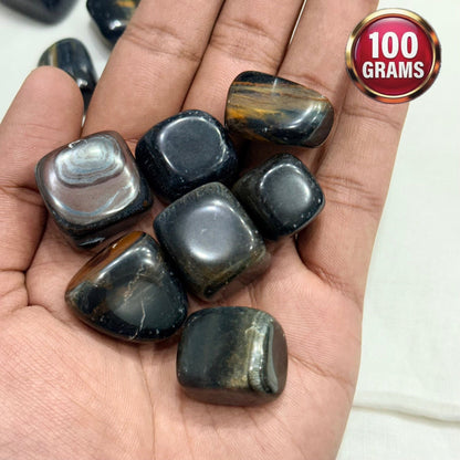 Natural blue tiger eye tumble stones in hand, polished oval shapes with golden bands