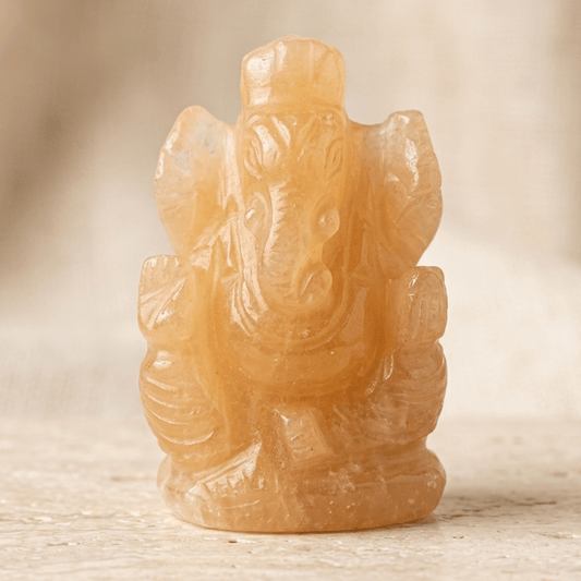 Natural calcite Ganesh Ji carving figurine with flowing details on a stone surface