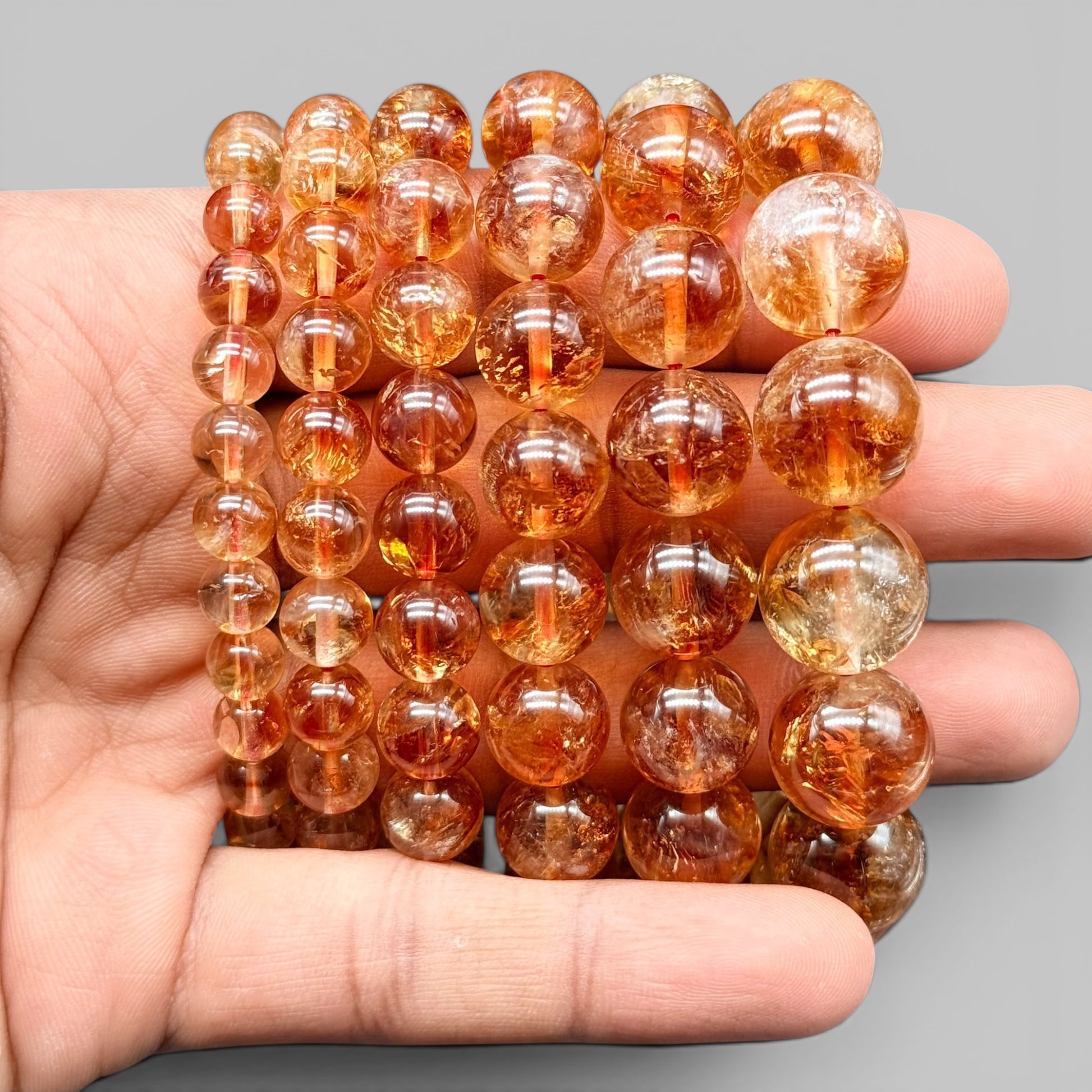 Natural citrine AAA bracelet beads held in hand, showing round amber-gold and clear stones