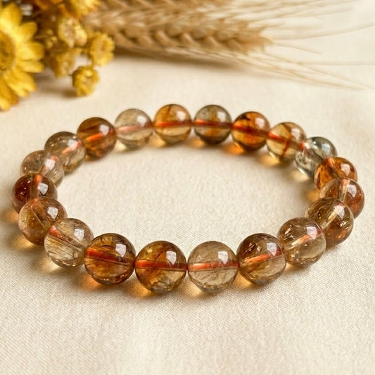 Natural citrine AAA bracelet in close view on light fabric background, round golden beads