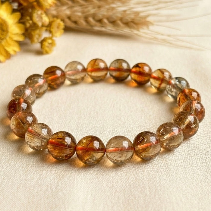 Natural citrine AAA bracelet in close view on light fabric background, round golden beads