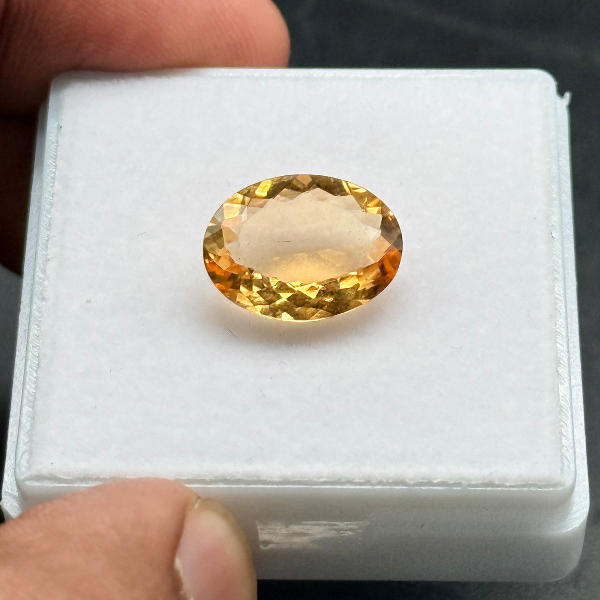 Natural citrine oval mixed cut gemstone side view in a plastic holder