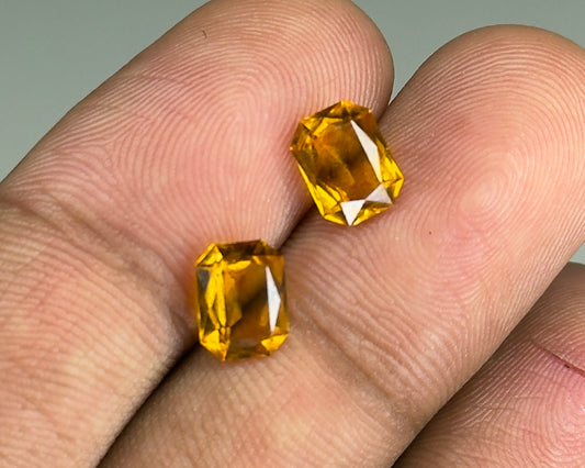 Natural citrine pair gemstones in yellow faceted cuts shown on fingertips