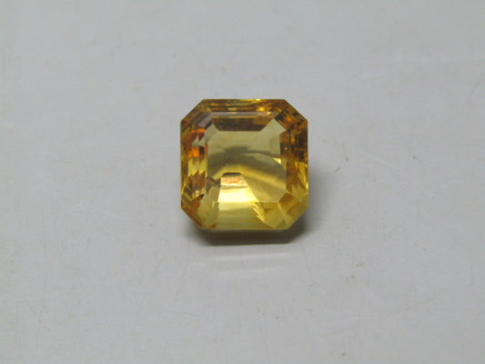 Natural citrine gemstone in a step-cut square, warm yellow center on a neutral background