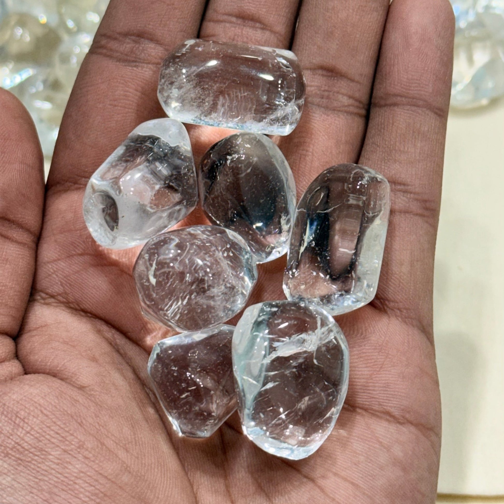 Hand holding natural clear quartz tumble stones for clarity meditation and energy cleansing