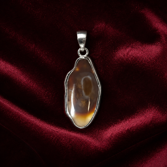 Natural fire agate oval pendant set in 925 silver on a dark red velvet background