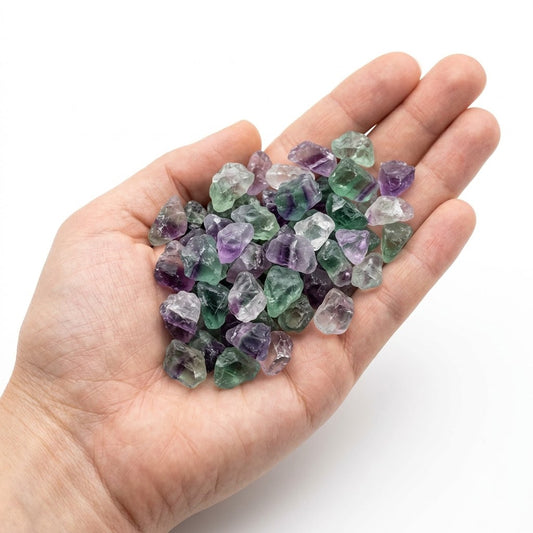 A hand holding a heap of natural raw fluorite chips on a white background