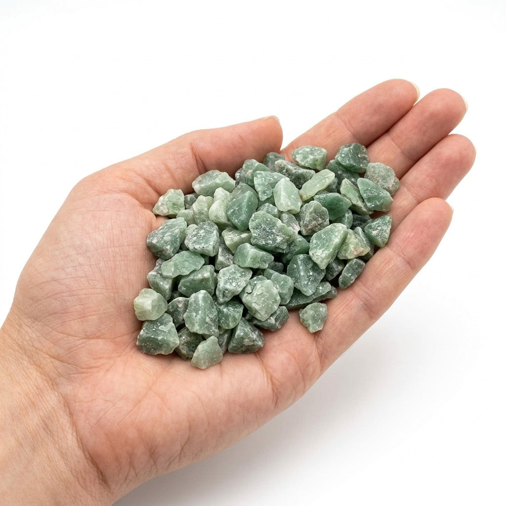 A hand holding a heap of natural raw green aventurine chips on a white background