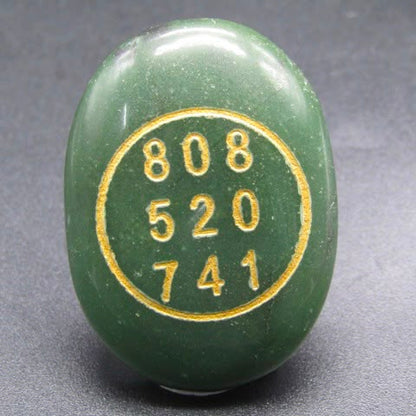 Natural green jade coin pendant back with gold number markings on gray background