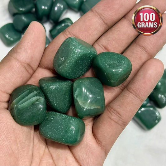 Natural green jade tumble stones in a hand, polished rounded pieces close up