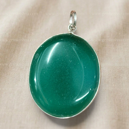 Close-up of natural green onyx locket pendant in silver-tone bezel on beige background