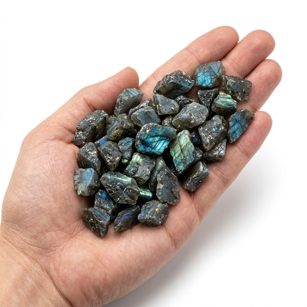 A hand holding a heap of natural raw labradorite chips on a white background