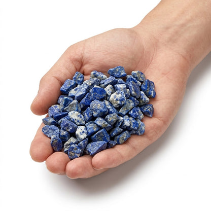 A hand holding a heap of natural raw lapis lazuli chips on a white background