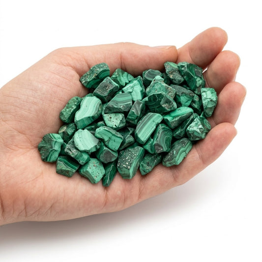 A hand holding a heap of natural raw malachite chips on a white background