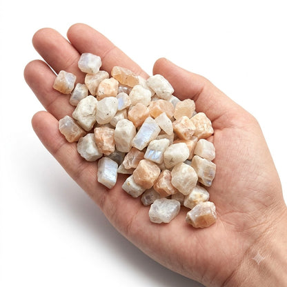 A hand holding a heap of natural raw moonstone chips on a white background