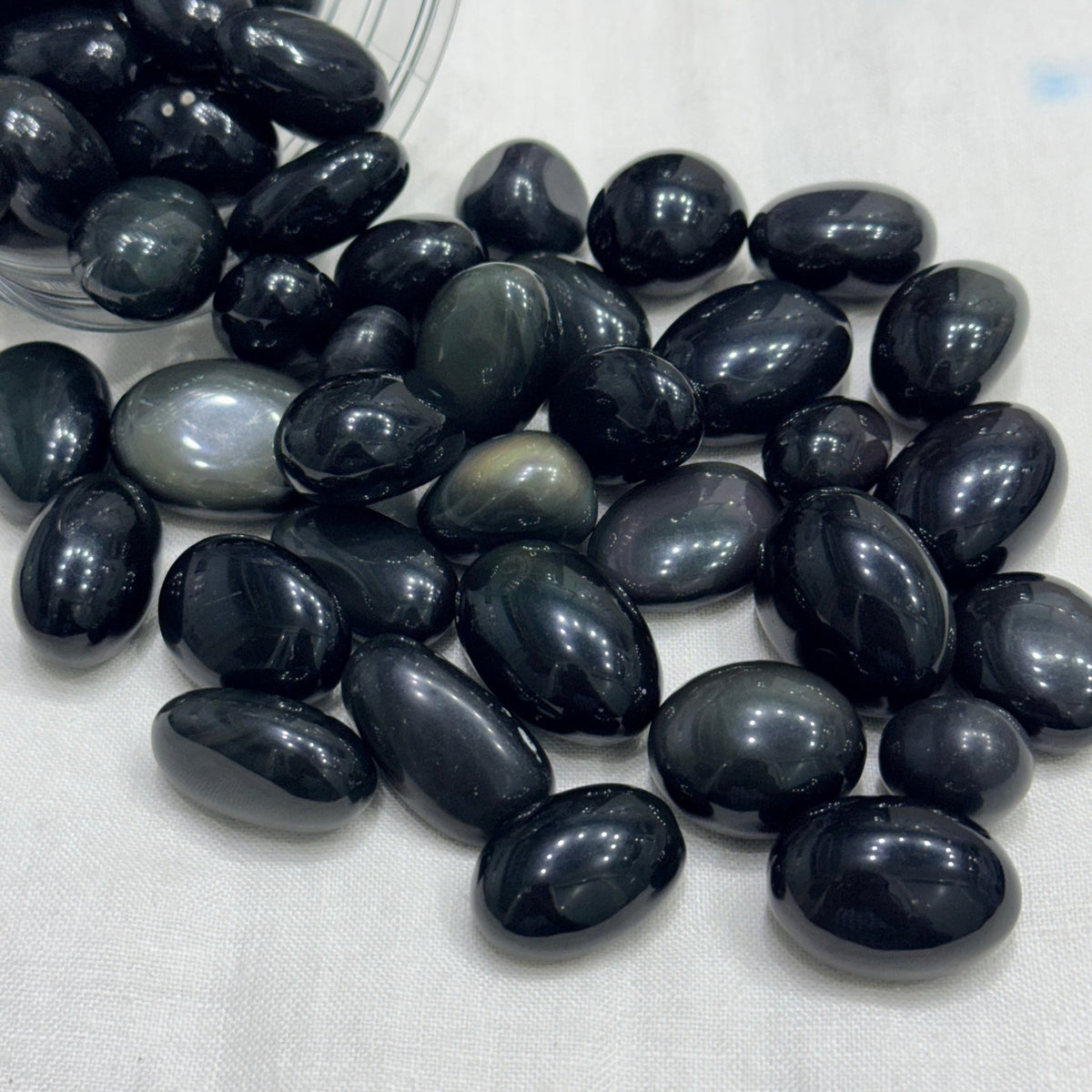 Natural rainbow obsidian tumble stones, glossy smooth protective rocks in a tray