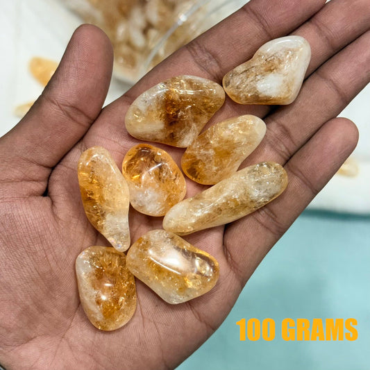 Natural raw citrine tumble gemstones held in a hand, polished golden yellow stones