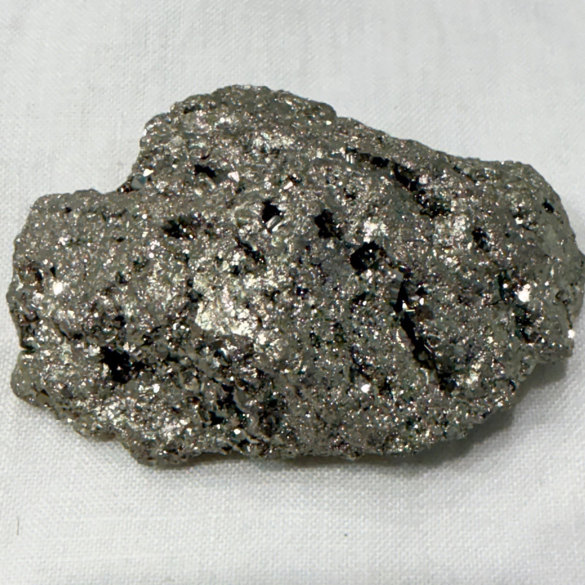 Natural raw pyrite crystal specimen with metallic sparkle, close-up on light background