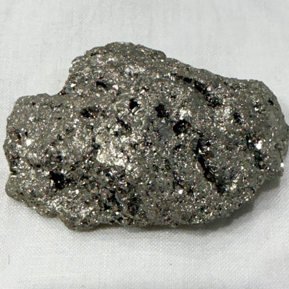 Natural raw pyrite crystal specimen with metallic sparkle, close-up on light background
