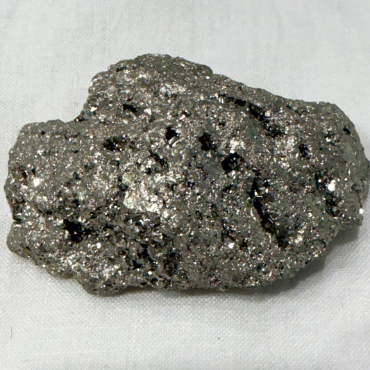 Natural raw pyrite crystal specimen with metallic sparkle, close-up on light background