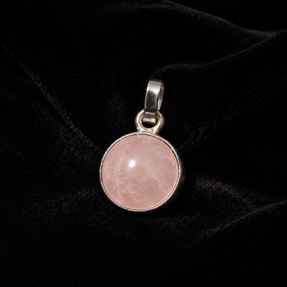 Natural rose quartz cabochon pendant in German silver round bezel on black fabric