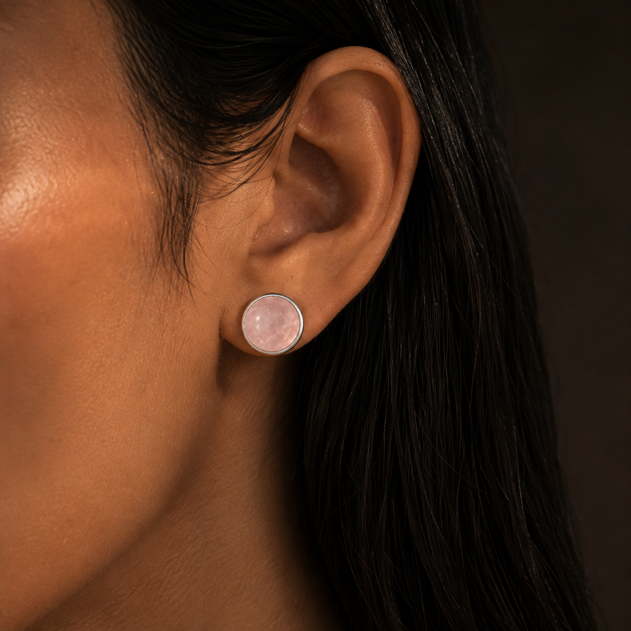 Close-up of natural rose quartz cabochon stud earring in German silver on ear