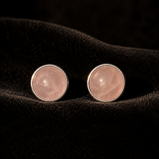 Natural rose quartz cabochon stud earrings in German silver, close-up front view on dark surface
