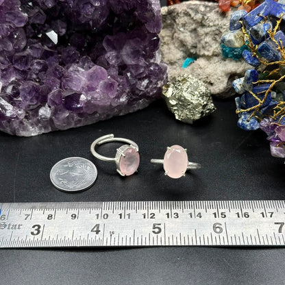 Natural rose quartz adjustable ring with pink oval stone on jewelry display and ruler
