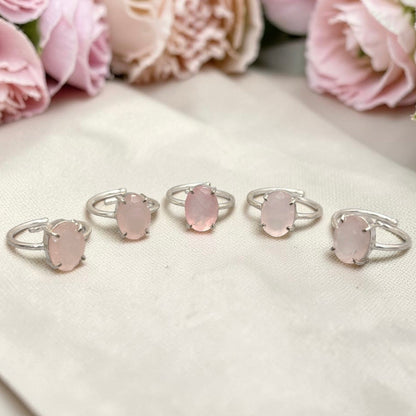 Natural rose quartz adjustable ring featuring a pink oval stone on white fabric background