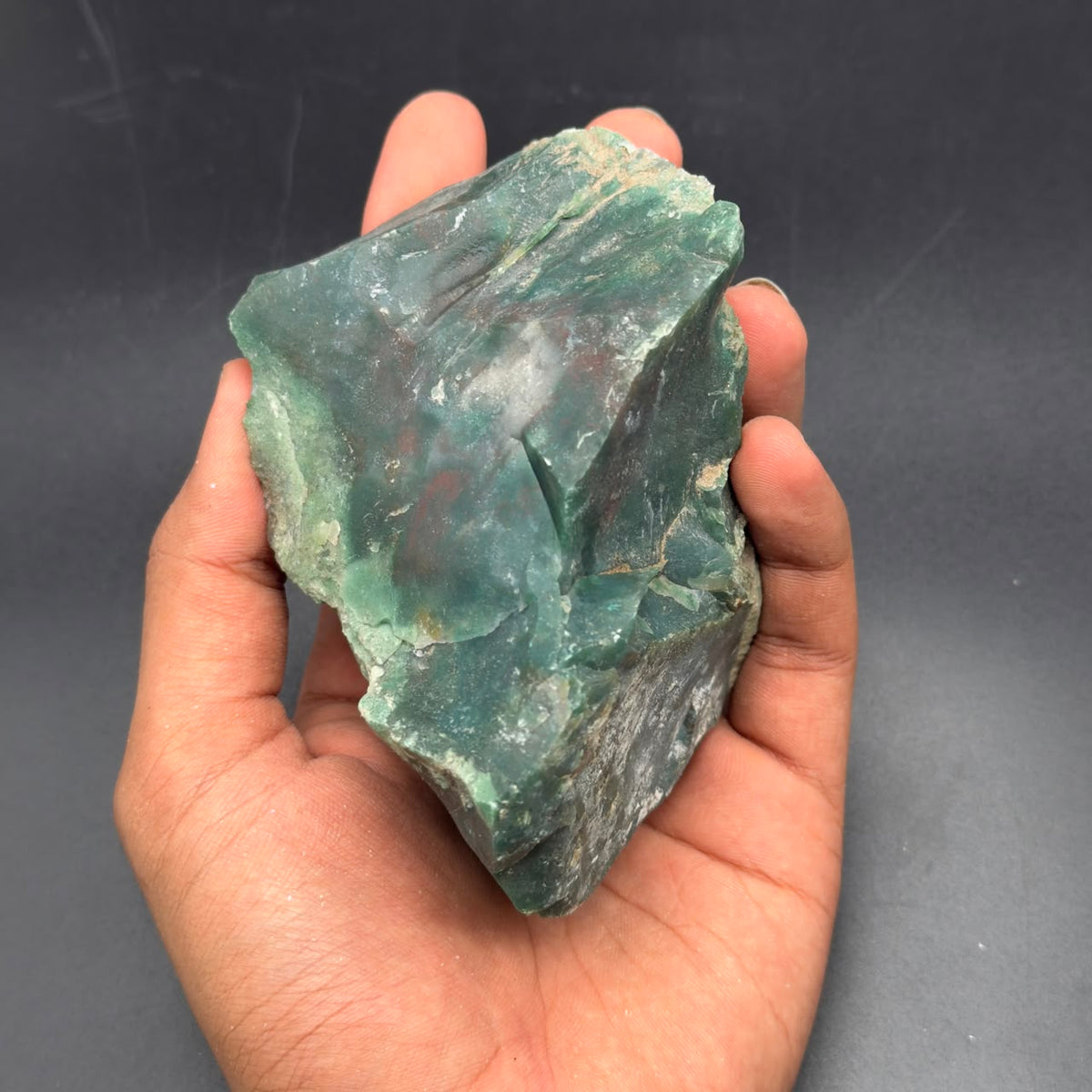 Natural rough bloodstone in green tones held in hand for scale