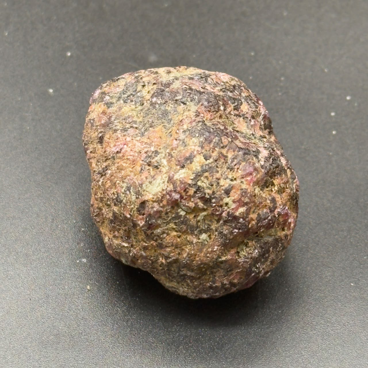 Natural rough hessonite garnet stone, rounded shape with speckled brown and green tones