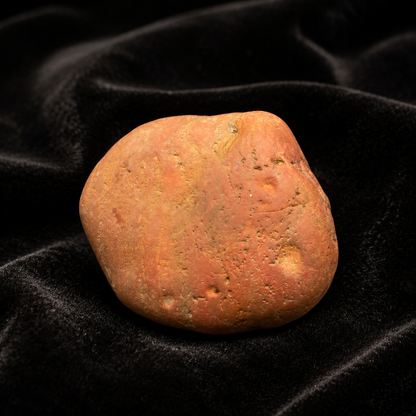 Natural rough red jasper stone with warm orange-red tones on black velvet