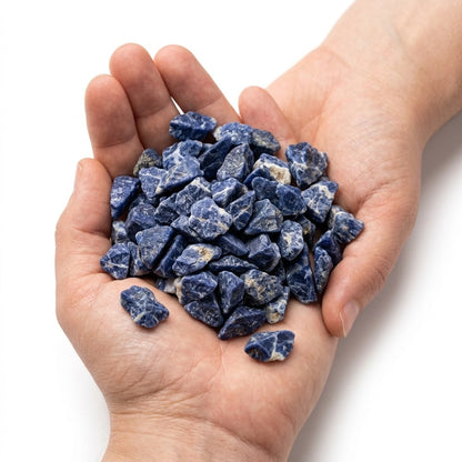 A hand holding a heap of natural raw sodalite chips on a white background