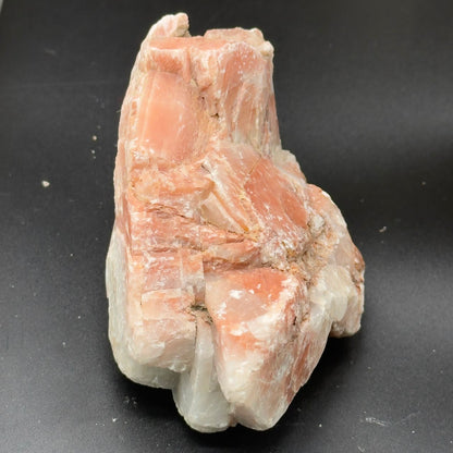 Natural sunstone rough crystal cluster with orange peach color and white streaks on dark base
