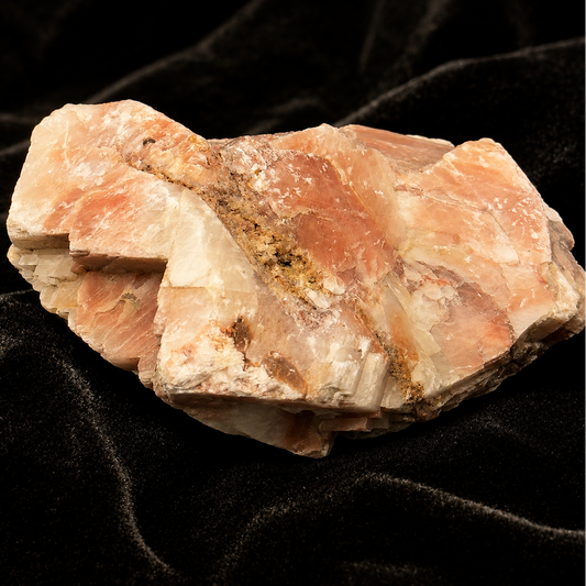 Natural sunstone rough crystal specimen with peach and cream tones on dark background