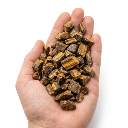 A hand holding a heap of natural raw tiger's eye chips on a white background