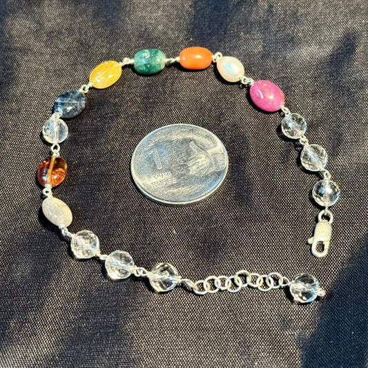 Navratna bracelet in 925 sterling silver with multicolor gemstone beads on dark fabric